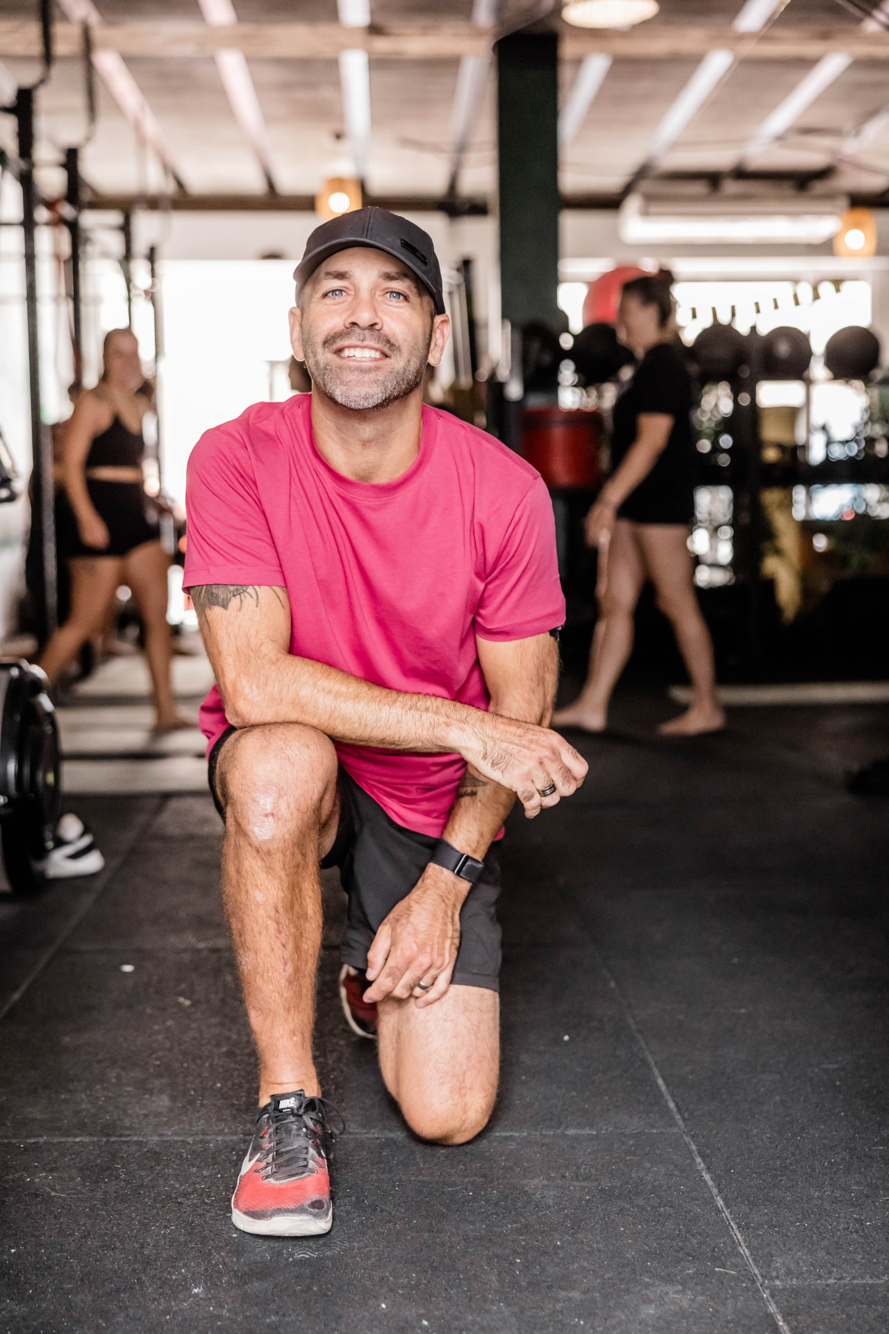 Brett kneeling on the floor of his CrossFit gym, smiling at the camera.